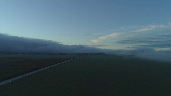 在大雾弥漫的早晨卡车行驶在宽阔的农田上