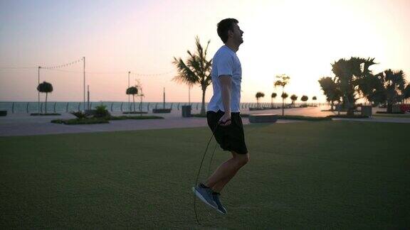 日落时分一名男子在海边的公园里进行跳绳运动