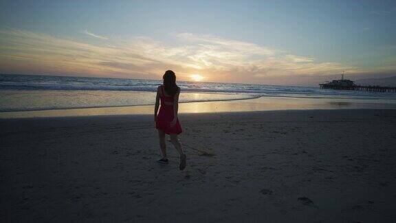 日落时分圣塔莫尼卡海滩上热情的女孩