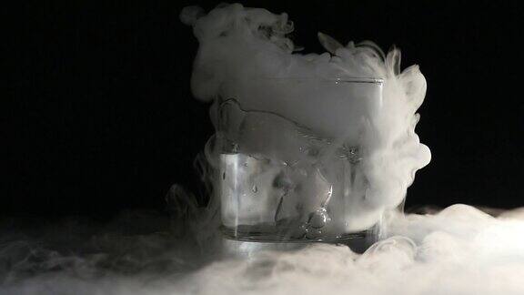 抽象的白烟在玻璃中干冰对黑暗背景的影响