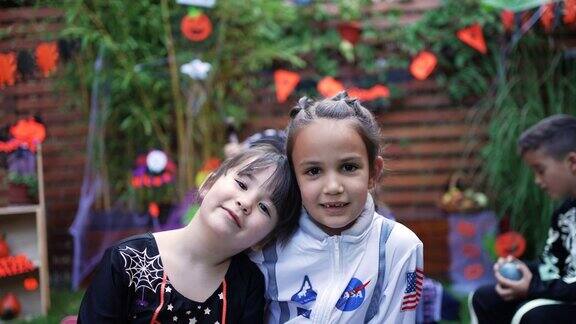两个可爱的姐妹在后院派对上穿着万圣节服装的照片