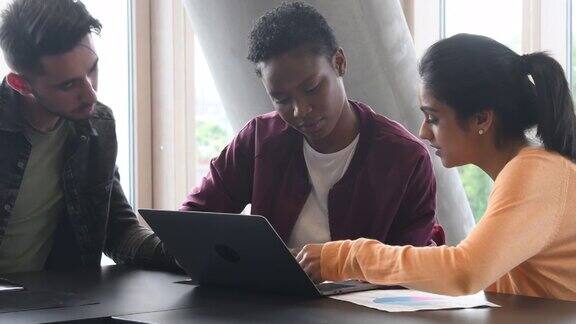 两个年轻的女人用笔记本电脑和男大学生聊天