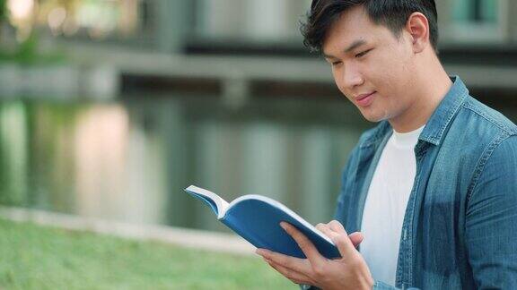 亚洲人大学的学生坐在校园草地上看快乐和在公园看书