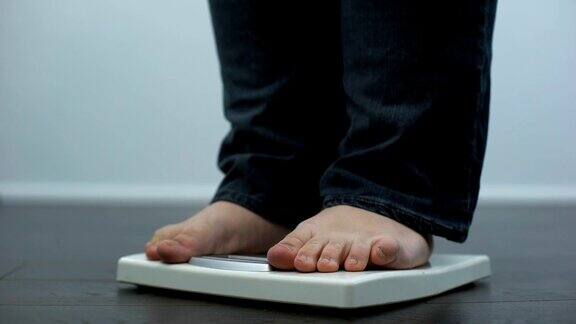 肥胖男性在磅秤上检查体重健康失调暴饮暴食结果
