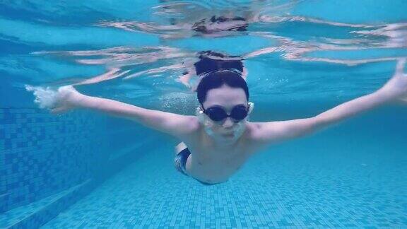 低角度看亚洲中国少年男孩游泳穿过游泳池在假期