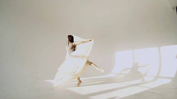 在白色的工作室里穿着古典芭蕾舞短裙的芭蕾舞女演员的剪影