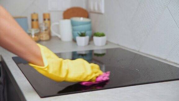 戴着橡胶手套的妇女正在清洁电磁炉