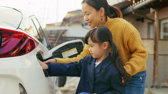 小女孩在家帮妈妈给电动汽车充电
