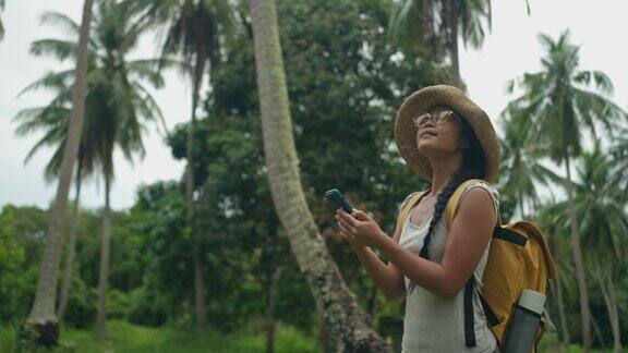 年轻的亚洲女性探索椰子森林使用智能手机导航