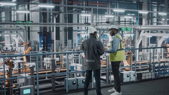 多种族经理和非裔美国汽车工厂工程师制服使用平板电脑汽车工业4.0制造员工在汽车装配厂讨论工作