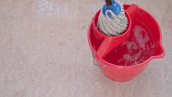 拖把在桶中清洗清洁粉红色的油毡地板
