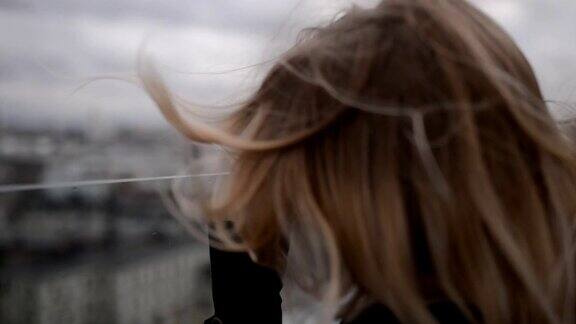 年轻女子站在屋顶上望着地平线