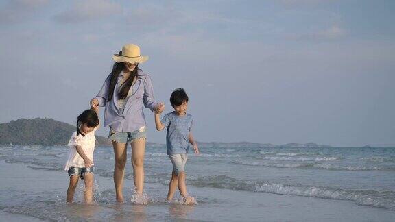 快乐的母亲和她的孩子享受和走在海滩上的暑假缓慢的运动家庭假期和旅游