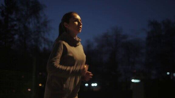 晚上慢跑女孩在夜城的背景下沿着河堤奔跑在户外练习的年轻女运动员
