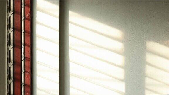 时间流逝:阳光透过百叶窗照到白色的混凝土墙壁上