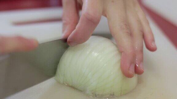 白种厨师用一把大菜刀将洋葱切成薄片