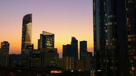 日落时摩天大楼的发光窗户阿布扎比的现代办公室和塔楼