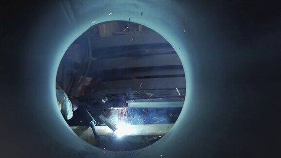 一名焊工正在通过一根大管子焊接金属摄像机角度