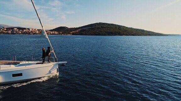 日落时分年轻的女子在帆船的甲板上享受微风