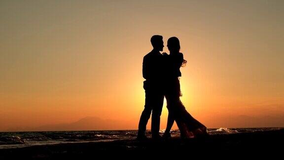 日落时海滩上一对浪漫情侣的剪影