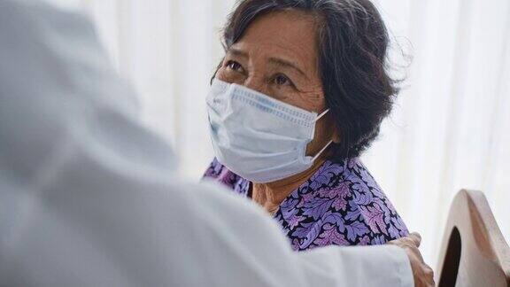 医生给一位戴着一次性医用口罩的老年患者精神支持慢动作