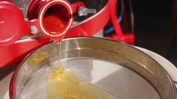 蜂蜜从滤器上流出滤器放在一个白桶里