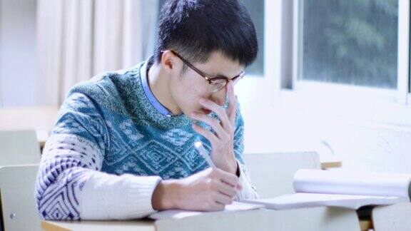 亚洲男子学生在窗户附近学习