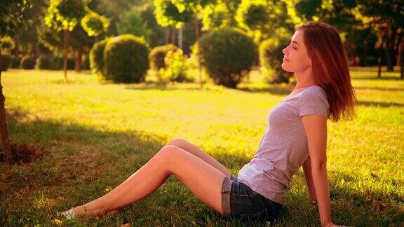微笑的女性摆姿势坐在草坪上