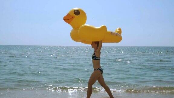 一个女人拿着充气鸭子走在空旷的海滩上