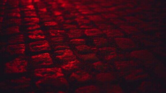 潮湿的红色灯光照亮鹅卵石铺街道在晚上