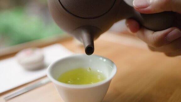 女用手将日本绿茶从罐中倒出