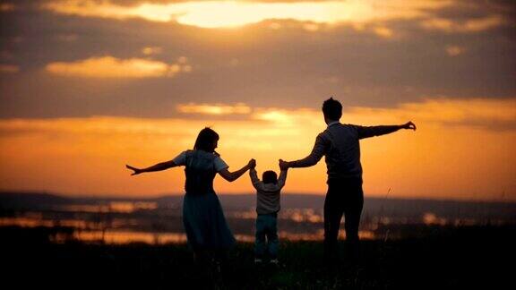 全家手牵爸爸妈妈在空中抚养宝宝一家人欢天喜地橘红色的夕阳夏日