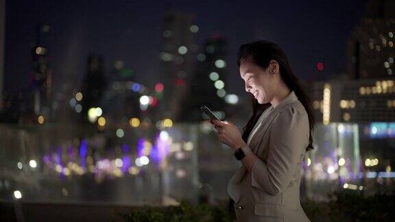 女商人晚上在城市里使用智能手机