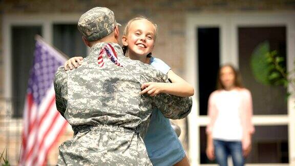 女儿跑着去拥抱父亲兵快乐的回家举着美国国旗
