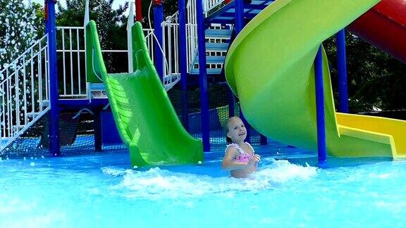 女孩在水上乐园玩水上滑梯(慢镜头)