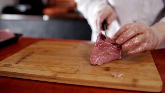 女厨师在餐厅的砧板上切猪肉