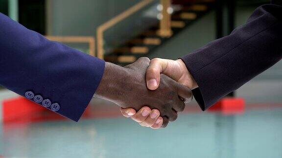 黑色和白色的人的手与商务服装在现代握手显示彼此的友谊和尊重