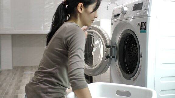 漂亮女人在自动洗衣机里洗衣服