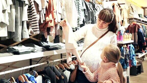 怀孕的母亲和年幼的女儿在挑选衣服