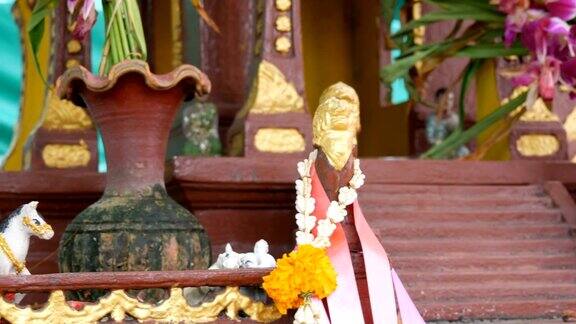 在一个花园里棕色的佛坛供祈祷者使用上面装饰着鲜花和各种小雕像
