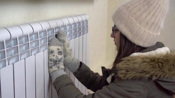 一个穿着冬季夹克戴着帽子和手套的小女孩用喷壶暖手屋子里很冷因为屋里禁止暖气4k