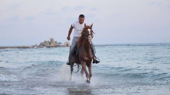 慢动作男子骑着棕色的马在海滩上疾驰