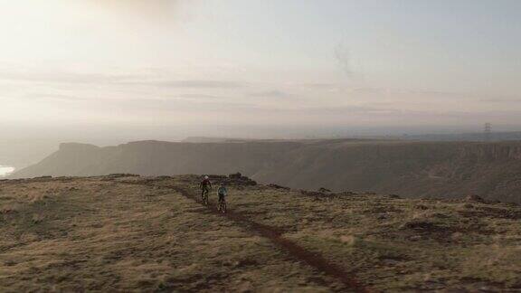 无人机拍摄的两个人在科罗拉多州丹佛市西部的落基山脉山地自行车与城市在日出