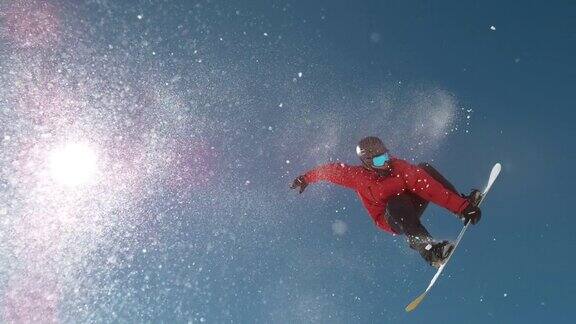从下往上:当滑雪者在做滑雪特技时雪花在阳光下闪闪发光