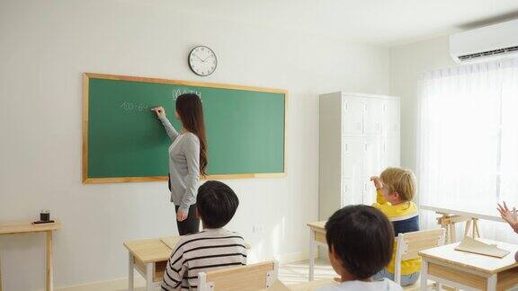 一群小学生在教室里跟着老师学习迷人美丽的女指导老师在幼儿园用快乐有趣的活动为幼儿讲解和教育