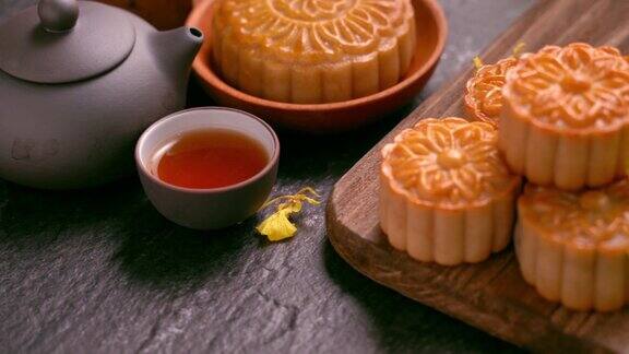 美丽的月饼在木托盘与茶和花在黑石板背景中国传统的中秋节观念