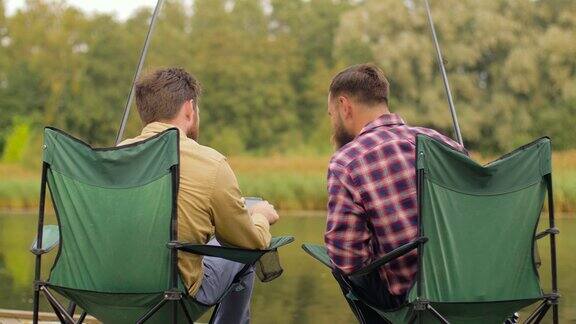 朋友们用智能手机在湖边钓鱼