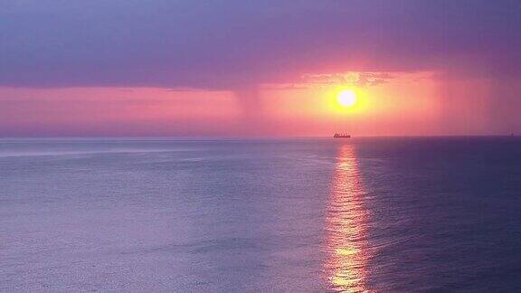 日出平静的海浪与美丽的蓝色丁香云和升起的太阳