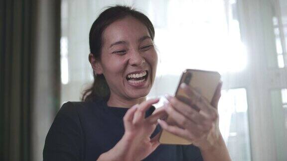 年轻的亚洲女性拿着智能手机庆祝获奖或欢呼手机奖