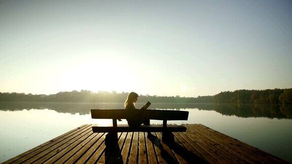 一个年轻女子在湖边的长椅上看书